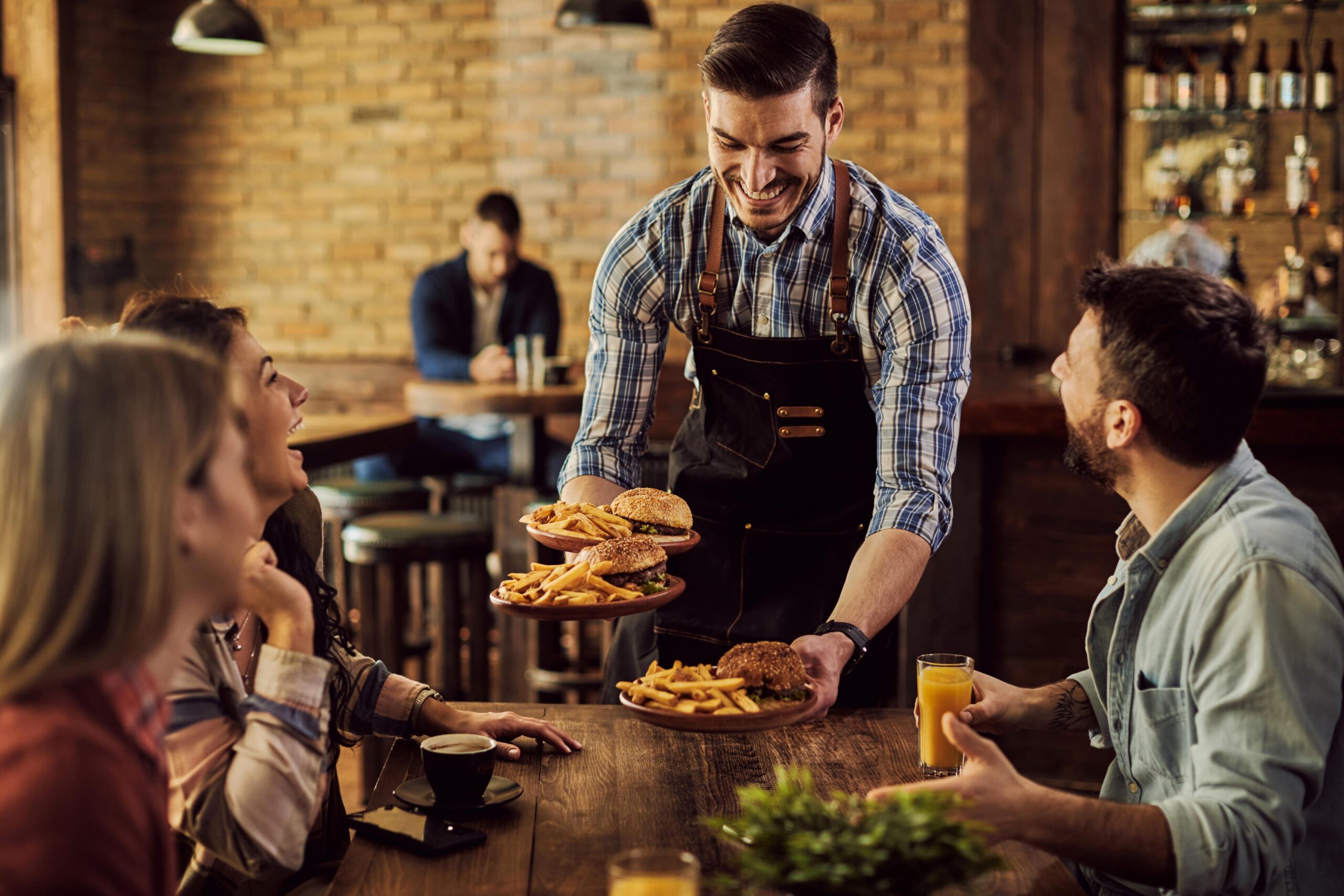 happy-waiter-serving-food-group-cheerful-friends-pub-min